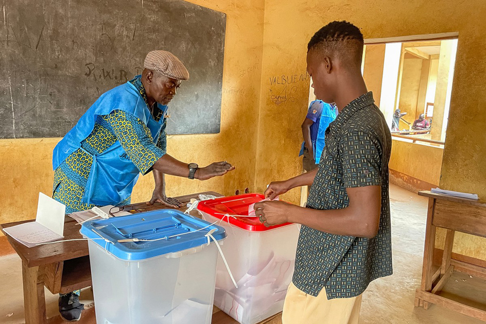 A voter (R) casts his ballot at a polling station in Bangui on December 28, 2025 during Central African Republic's presidential election. (Photo by Annela NIAMOLO / AFP)