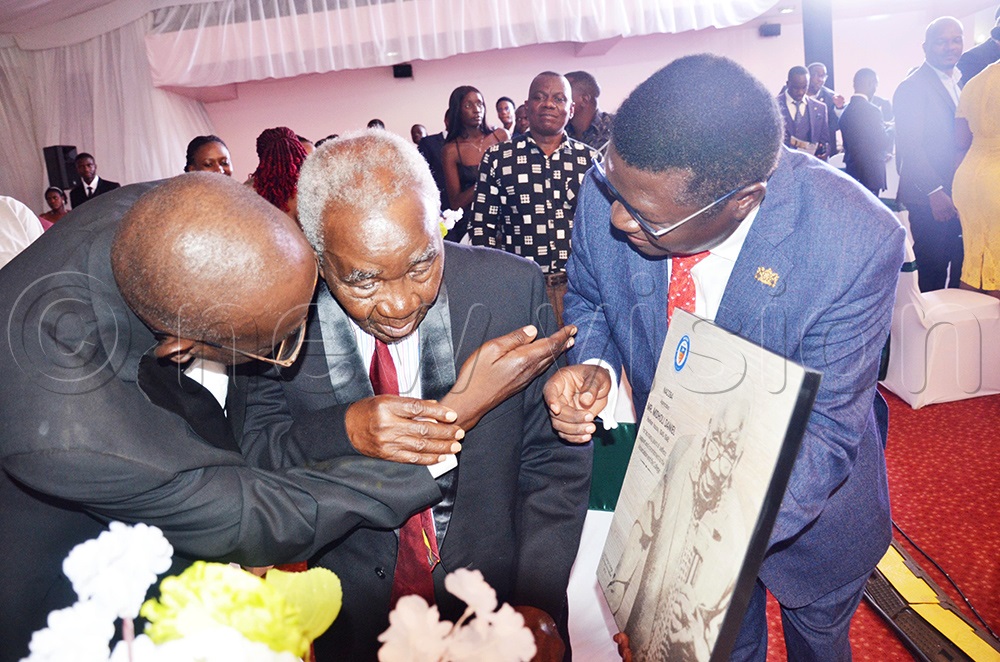 Minister of Justice and Constitutional Affairs, Nobert Mao handing over a gift to the oldest Namilyango old boy Daniel Midholi. (Photo by Isaac Nuwagaba)