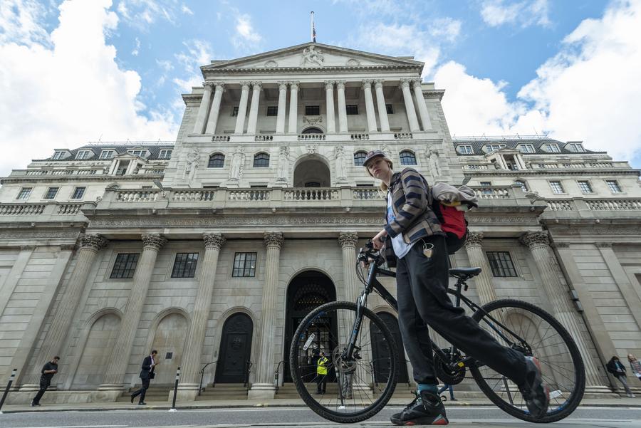 A woman walks past the Bank of England in London, Britain, on April 13, 2022. (Photo by Xinhua)