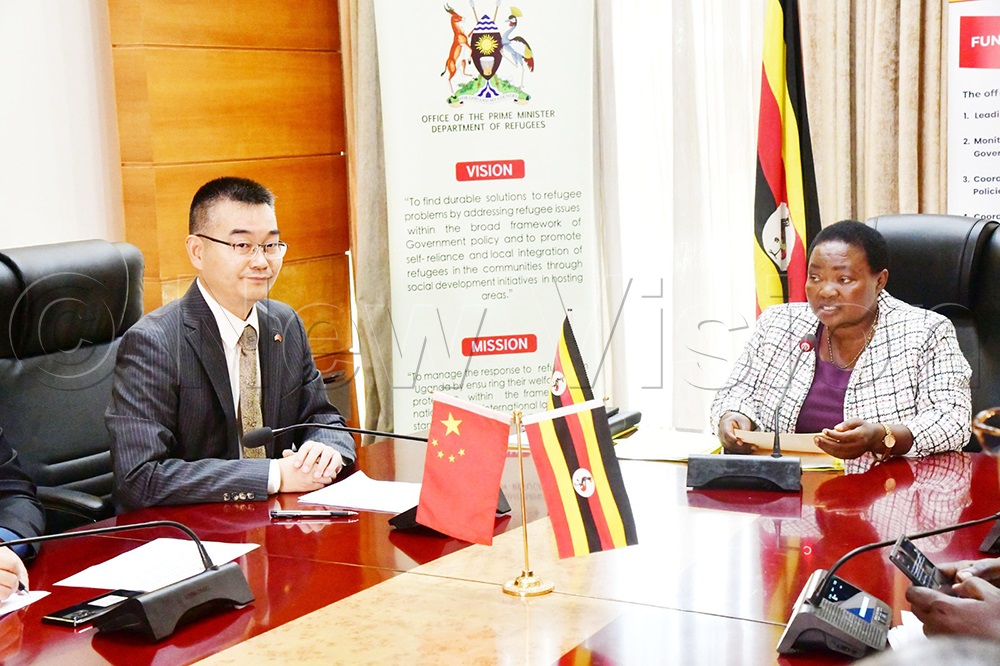 Fan Xuecheng, Charge d'Affaires ad Interim of the Chinese Embassy (left), looks on as Rt Hon. Robinah Nabbanja. Prime Minister of the Republic of Uganda makes her remarks during the launch of the OPM-China Emergency Humanitarian Cash Assistance Project. (Credit: Mpalanyi Ssentongo)