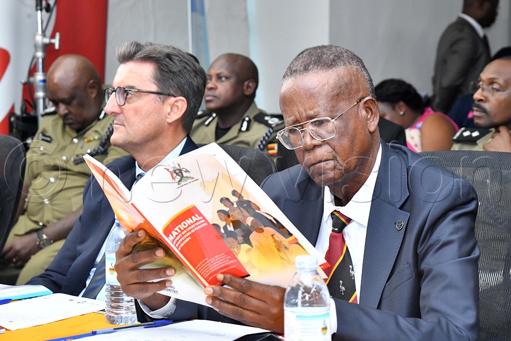 Minister of Internal Affairs Prof. Ephraim Kamuntu reading through the national report on countering trafficking in persons in Uganda. (Photo by Richard Sanya)