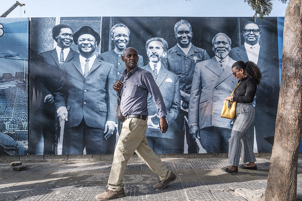 People walk in front of a banner in the city of Addis Ababa. 
