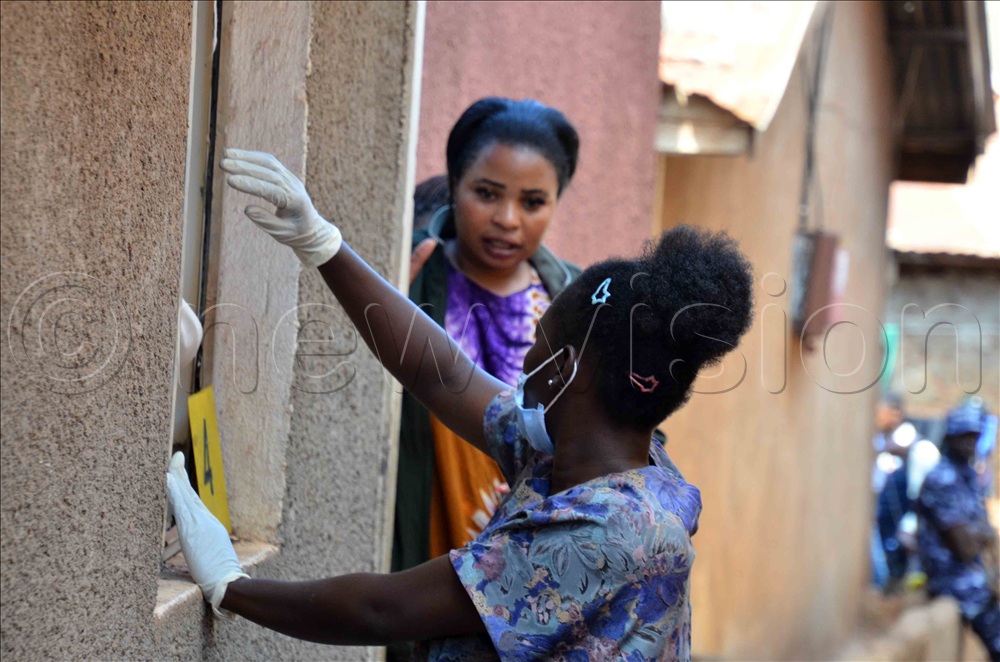 Rose Tusiime (L) showing the crime scene officers how the killer smashed her window during a scuffle