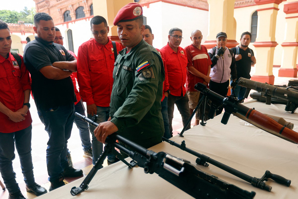 A member of the presidential guard displays weapons during an induction ceremony for individuals who enrolled in the Bolivarian National Militia enlistment campaign called by the government of President Nicolas Maduro at the 4F military museum in Caracas, on August 23, 2025. (Photo by Pedro MATTEY / AFP)