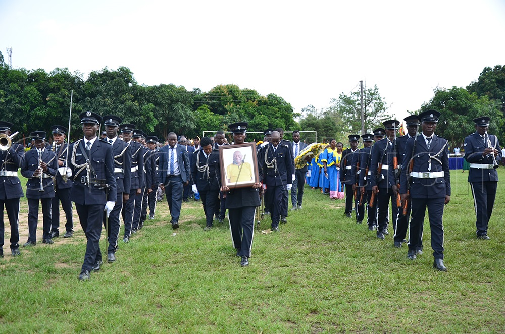 Police officers escort the casket to the burial grounds. (Photo by Jonan Tusingwire)