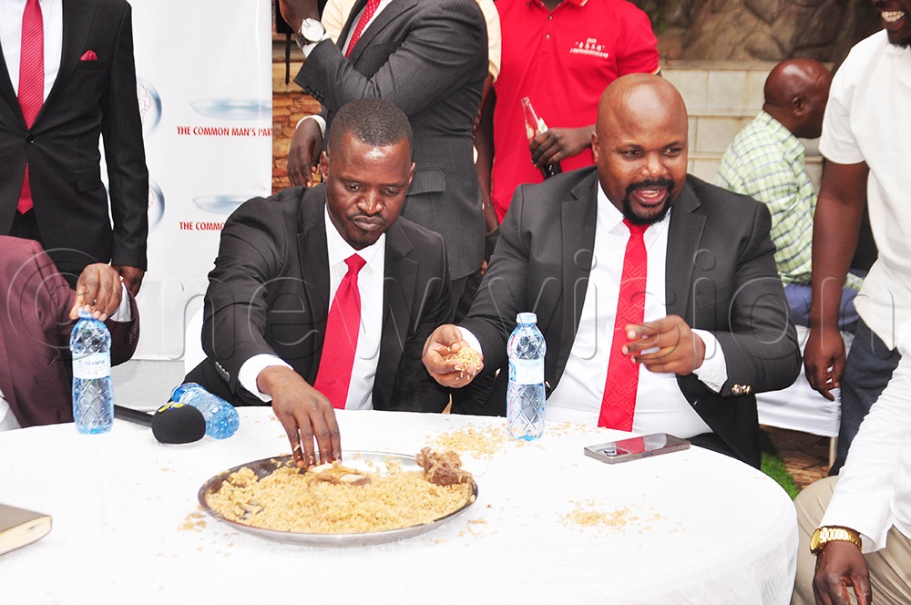 Common Man's Party (CMP) secretary general Moses Bigirwa and party president, Mubarak Munyagwa eating pilao on a platter, a party symbol for resource sharing. (Photo by Isaac Nuwagaba)