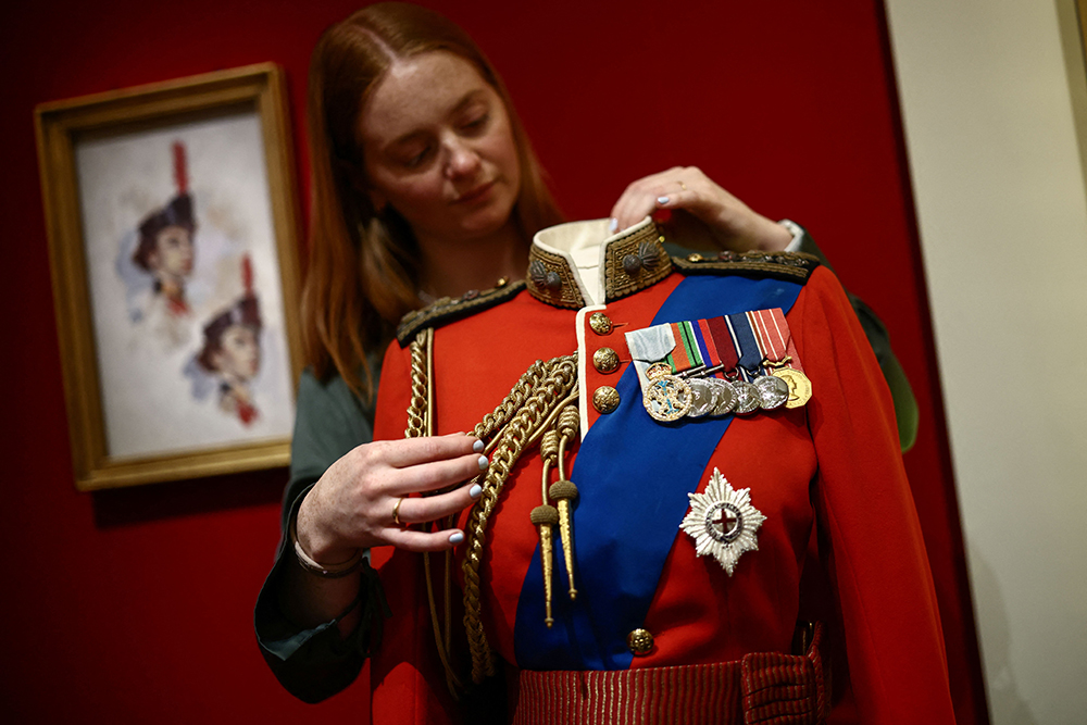 A member of the Royal Collection Trust staff poses with a full dress tunic of the Colonel-in-Chief of the Grenadier Guards, 1952, during a media preview of the exhibition 'Queen Elizabeth II: Her Life in Style' at the King’s Gallery in Buckingham Palace in London on April 9, 2026.