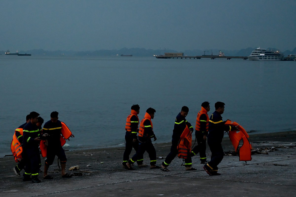 Rescuers walk on the wharf after searching for victims of a capsized tourist boat in Ha Long Bay, Quang Ninh Province on July 20, 2025. (Photo by Nhac NGUYEN / AFP)