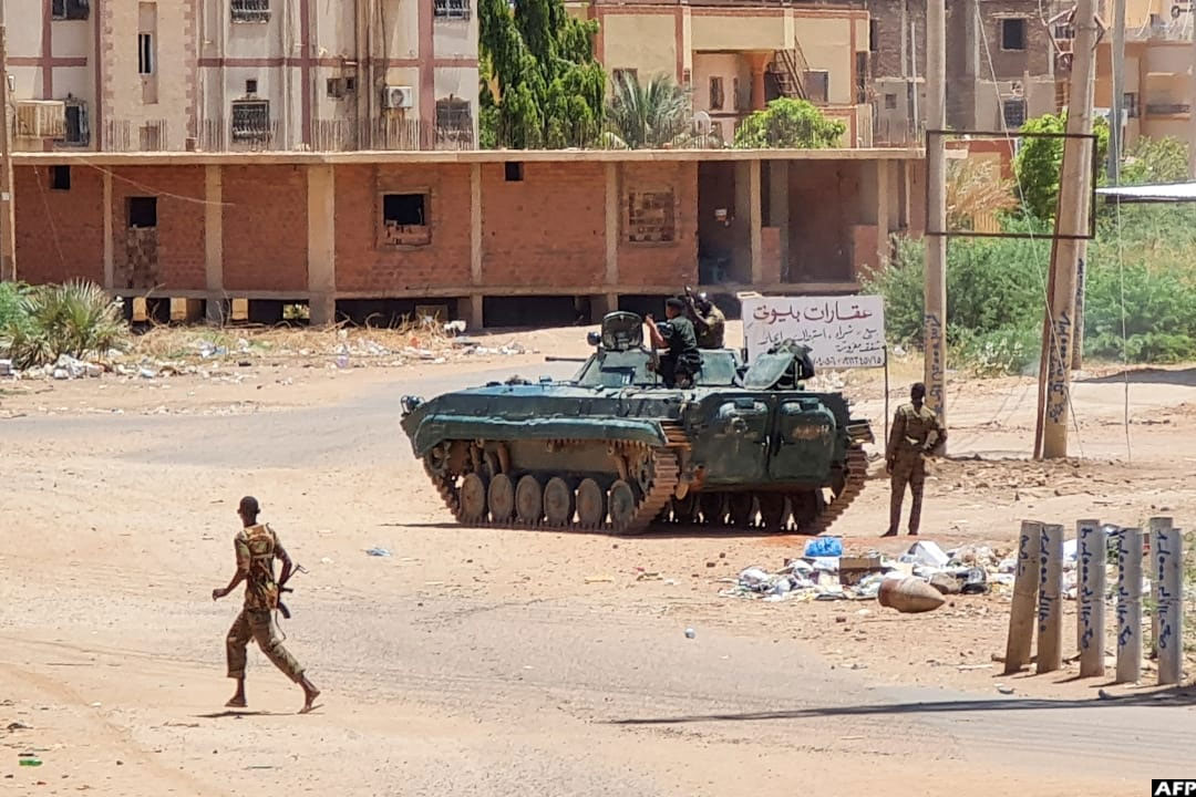 Sudanese Army soldiers walk near armoured vehicles stationed on a street in southern Khartoum, on May 6, 2023, amid fighting against the paramilitary Rapid Support Forces