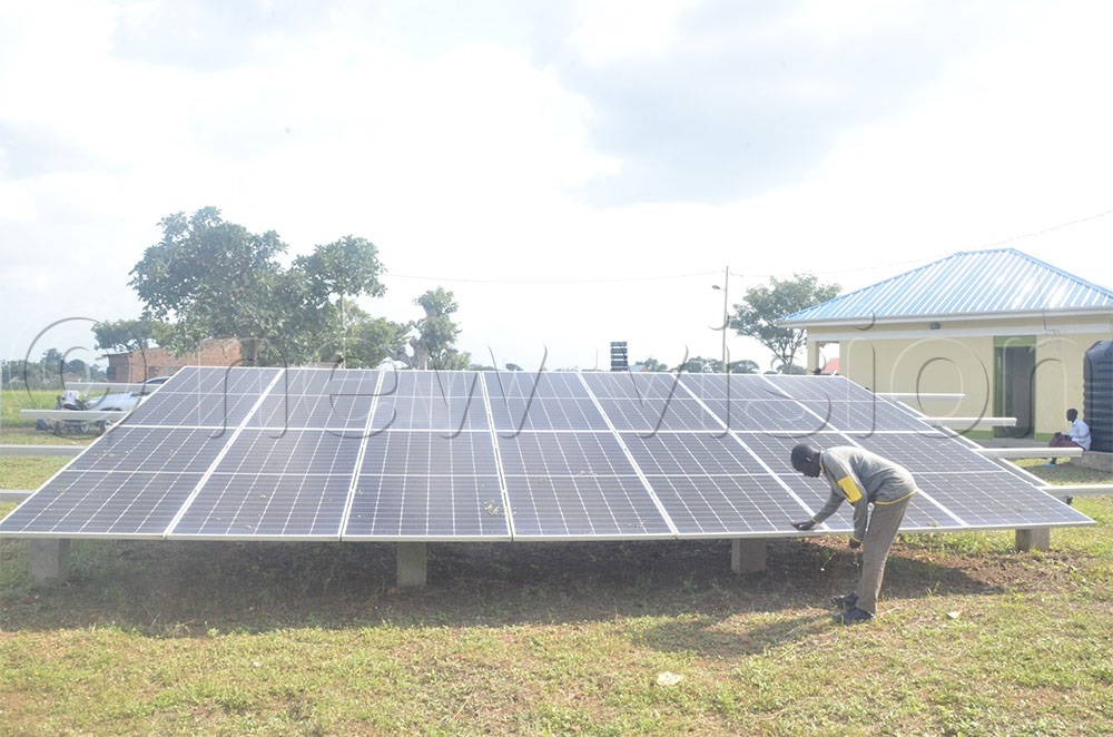 A man demonstrates how to clean solar panels to enhance their efficiency during a recent visit by technical staff and officials from the local government ministry to the Kanapa Solar mini grid in Magoro Sub-county, Katakwi District. (Credit: John Masaba)