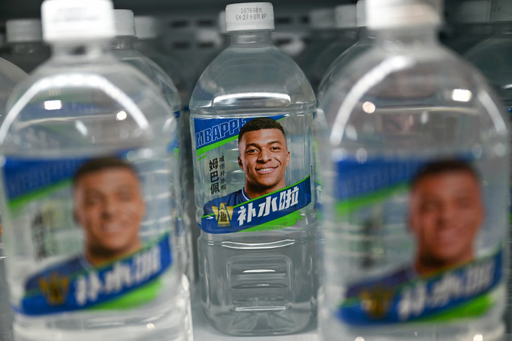 Bottles of Dongpeng Beverage Group's "Bushuila" electrolyte drink featuring French football star Kylian Mbappe on the packaging are displayed at a convenience store in Beijing on October 27, 2026. (AFP)