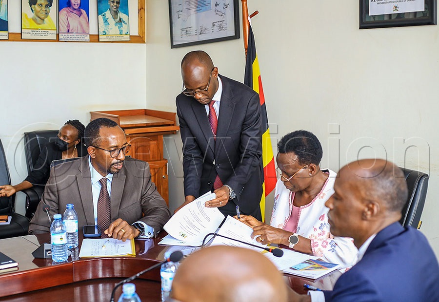 Ministry of Education and Sports Permanent Secretary Kedrace Turyagyenda (second right) signs an MOU with Francis Kahiriita Ngabirano, Under Secretary for Logistics at the Ministry of Defence and Veteran Affairs (far right), as NCS board chairman Ambrose Tashobya (left) looks on. Photo by Fred Kisekka
