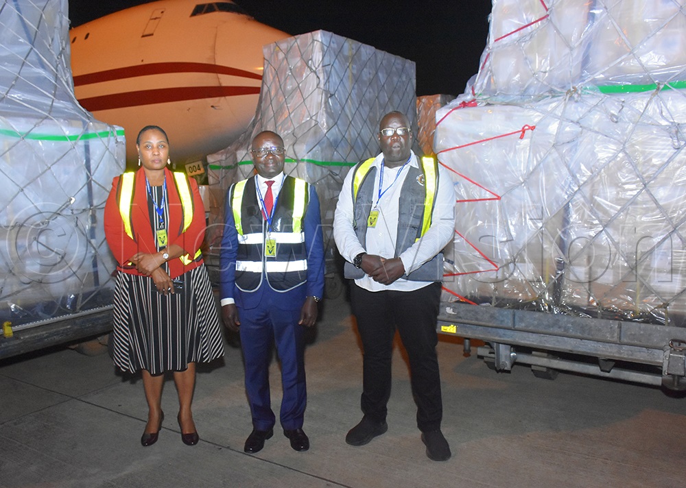 Justice Byabakama (centre) with commissioner Carol Beinamaryo and James Peter Emorut posing for a group photo infront the consignments of biometric voter verification kits at Entebbe airport on Monday night. (Credit: Julius Luwemba)