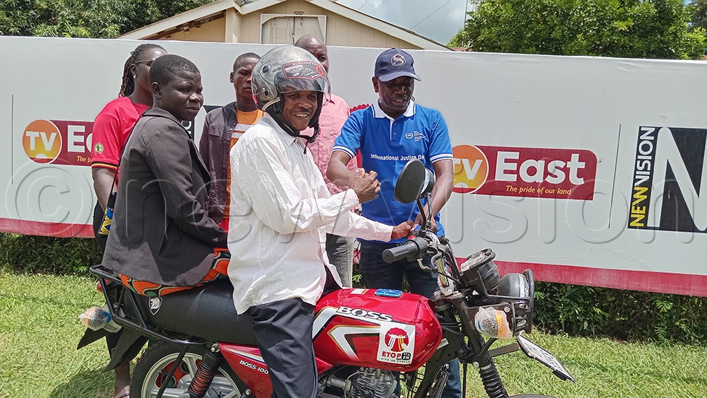 Patrick Oluk handing over a brand new motorcycle to the winner, Okiria, and his wife. (Credit: Juliet Akello)