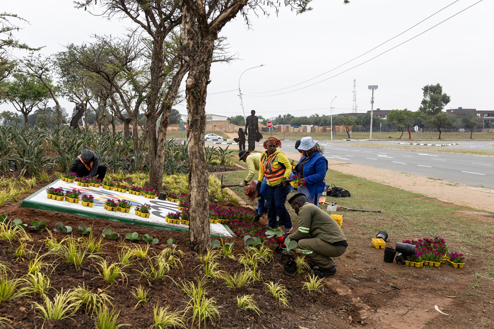 Workers plant flowers next to a G20 logo outside the NASREC Expo Centre in Johannesburg on November 4, 2025 where the upcoming G20 summit will be hosted. (AFP)