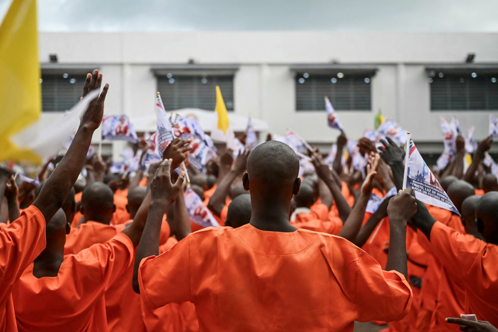 Inmates pray and wave flags bearing images commemorating the visit of Pope Leo XIV during his visit to Bata Prison in Bata on the tenth day of an 11-day apostolic journey to Africa, on April 22, 2026. (AFP)