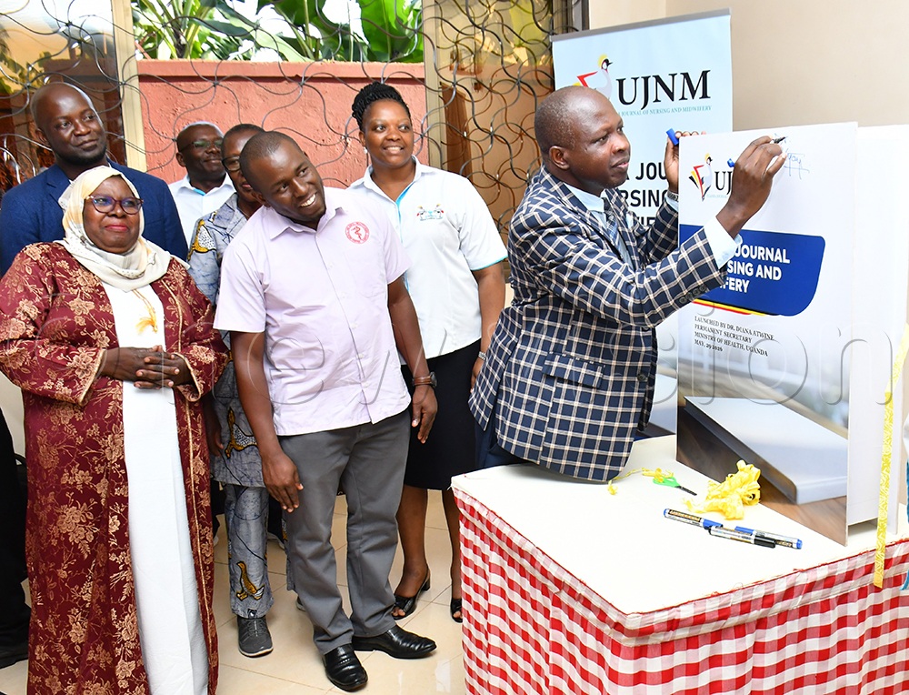 Dr. Alfred Yayi (R) the Senior Executive Consultant of Jinja Regional Referral Hospital launching the Nurses and Midwives Journal at Nile Hotel in Njeru Municipality on May 29th as the Commissioner Health and Education Training Hajati Dr. Safina Musene (L) and board members of the Uganda Nurses and Midwives Council look on. (Credit: Donald Kiirya)