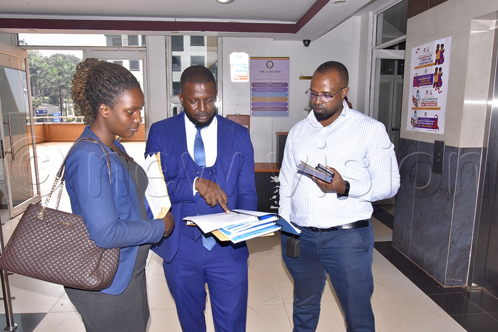 Nico Kayongo (middle), one of the traders lawyers who delivered the traders' petition to the Civil Division of the High Court, having a brief discussion with his colleague and Katongole at Twed Plaza. (Photo by Moses Kigongo)