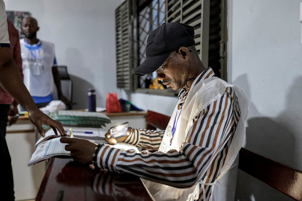 An officials of the General Directorate of Elections (DGE) checks a voter's information at a polling station in Conakry on December 28, 2025 before polls open during Guinea's presidential election. (Photo by Patrick MEINHARDT / AFP)