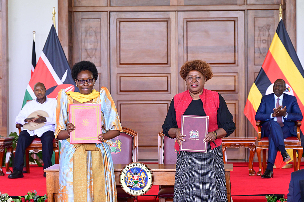 Uganda's Lands Minister Judith Nabakooba and her Kenyan counterpart after signing an MOU at Nairobi State House on Wednesday. Looking on (in background) are President Museveni (L) and President Ruto (R). (PPU)