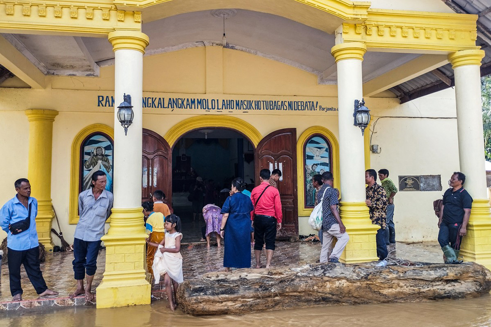 Batak Christian Protestant Church (HKBP) members arrive from evacuation shelters to attend a Christmas Eve mass at a flood-ravaged church in the Hutanabolon village of Central Tapanuli, North Sumatra on December 24, 2025. 