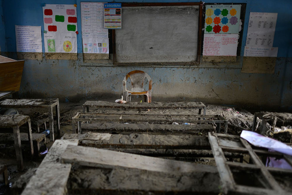 School benches and a teacher's chair are seen inside a classroom heavily covered in mud in the aftermath of flash floods at Bageshwori Secondary School in Galchi town of Nepal's Dhading district on August 30, 2026. (Photo by Manan VATSYAYANA / AFP)