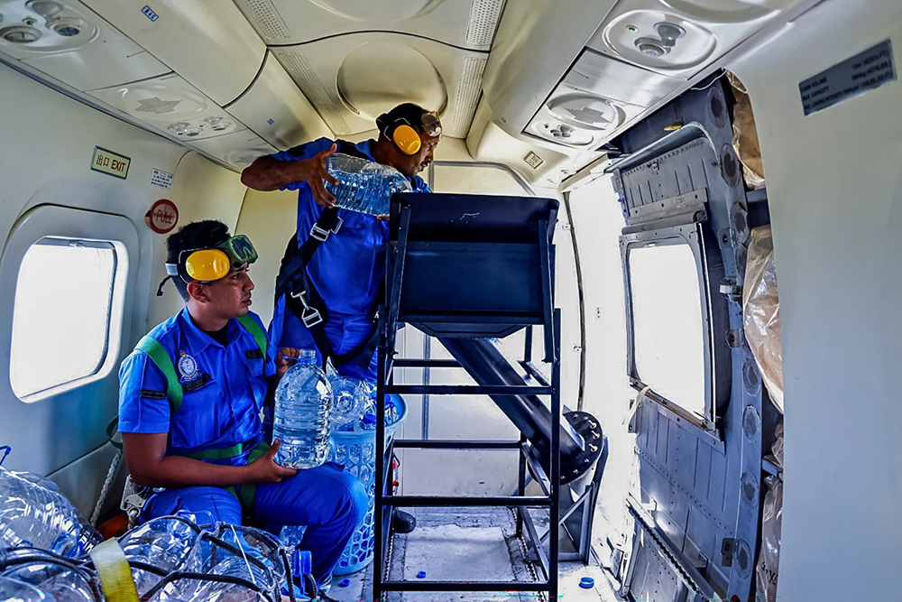 This handout photograph released by the Sri Lankan Air Force on September 20, 2026 shows airmen aboard an aircraft dispersing holy water over the island’s drought-hit areas seeking rain.