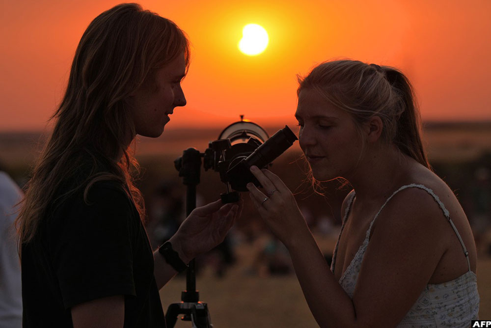 Two women observe the Moon uncovering the Sun in the moments following totality of the solar eclipse in Lodoso, Burgos province, on August 12, 2026