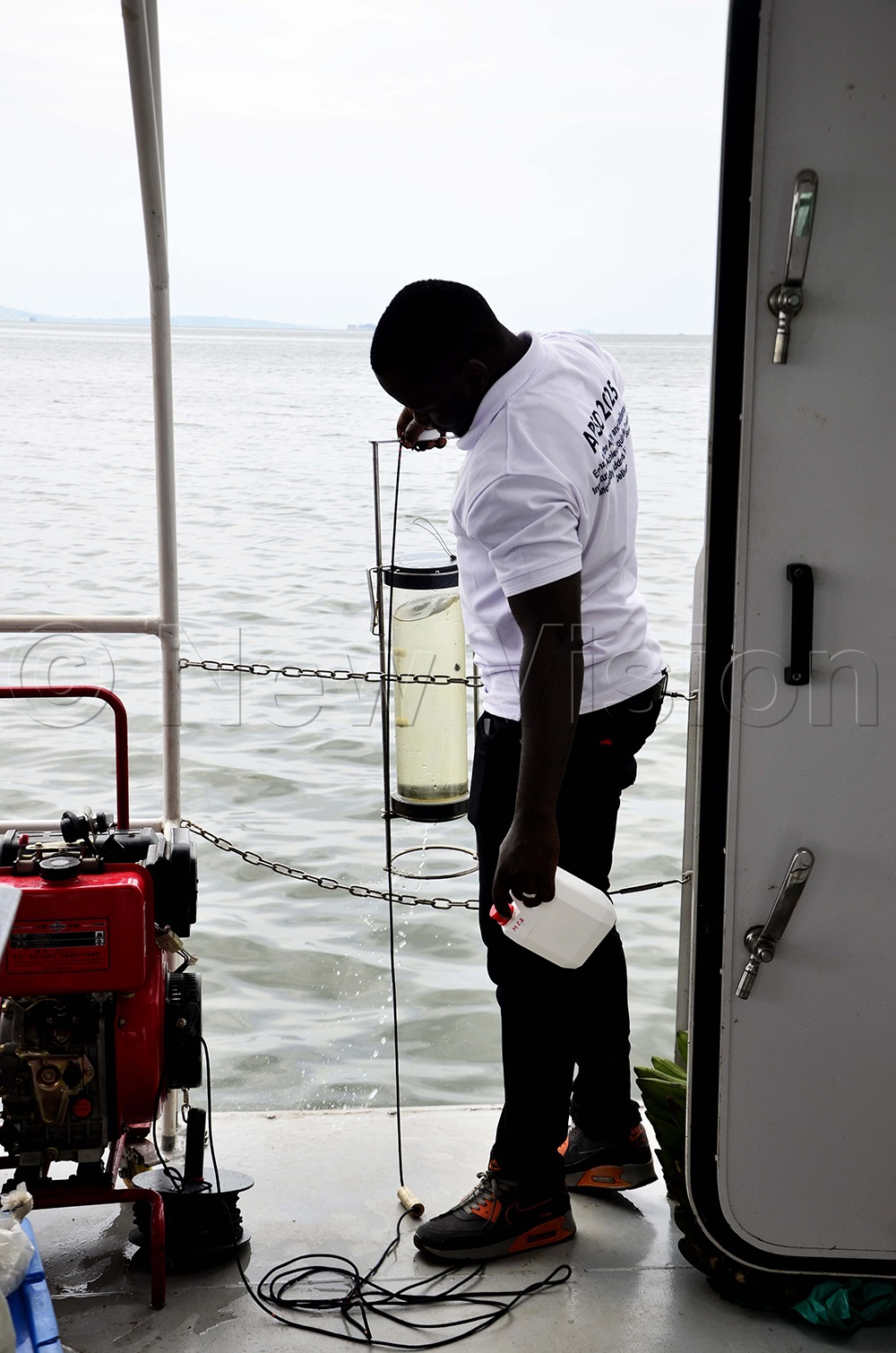 Water analyst collecting water samples to analyze the level of contamination in the Lake Victoria. (Photo by Juliet Kasirye)