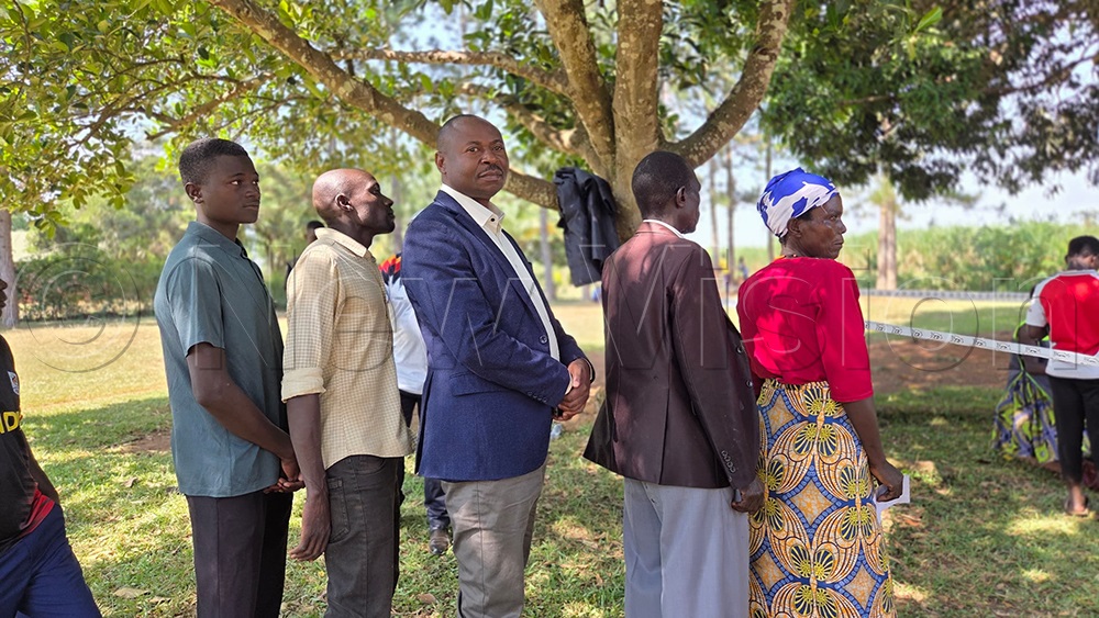 Paddy Kisembo (centre) lines up with other voters as they wait to cast their votes. (Photo by Peter Abaanabasazi)