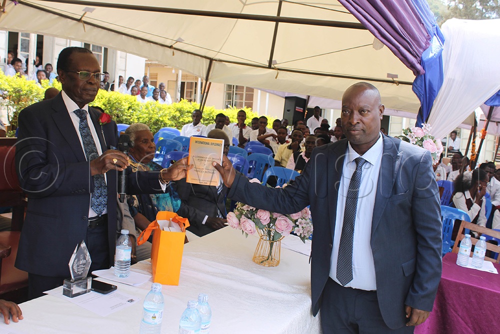 Former Speaker of the Parliament of Uganda, Ambassador Francis Butagira (left), handing over a copy of his book to the head teacher of Bugamba Secondary School, Robert Kihumuro Kijongoma (last on right), at the reunion of Bugamba SS in Rwampara district. (Photo by Abdulkarim Ssengendo)