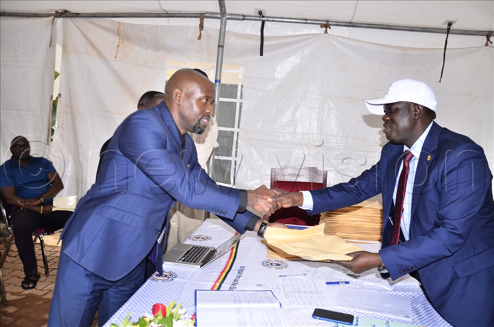 An aspiring presidential candidate Basaija Charles (left) receive an envelope contains nomination forms from the Principal Election Officer, Samuel Kiyingi (right) during pick of forms for presidential candidates at Electoral Commission offices in Kampala on 11 Aug 2025. 