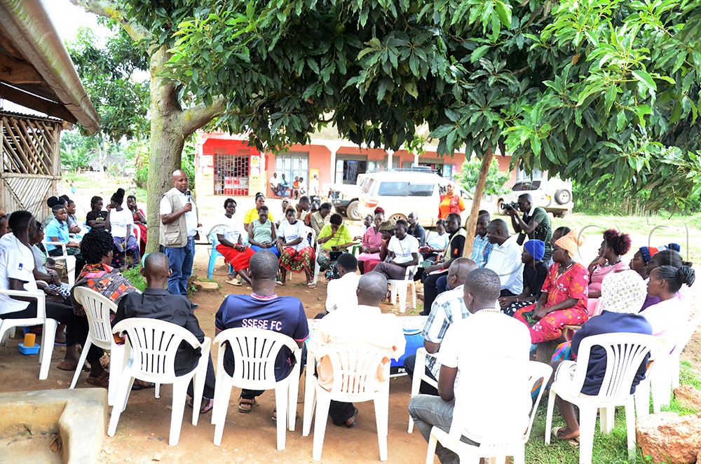 Dr. Patrick Kagurusi (centre standing), the Amref Health Africa Uganda Country Manager addressing some of the residents of Kasekulo landing site, Kalangala district in a meeting on the fight against Gender Based Violence.  This was during a joint monitoring of interventions under the Heroes for Gender Transformative Action program in Kalangala district on Wednesday. (Credit: Lawrence Mulondo)
