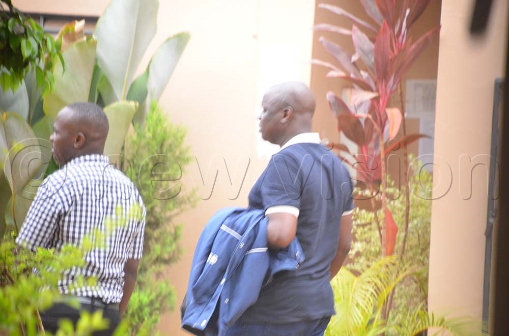 Assoc. prof.  Willy Okullu (R) being led to Kabalagala Police cells upon his arrest on August 05th, 2025. (Credit: Stuart Yiga) 