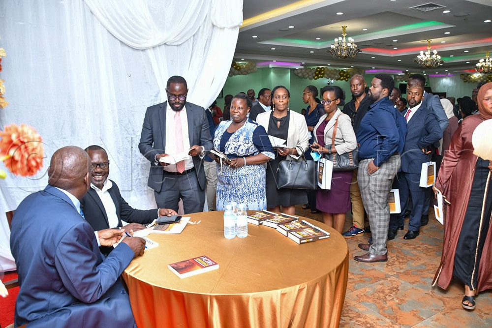 Justice Mike Chibita autographs books for guests.