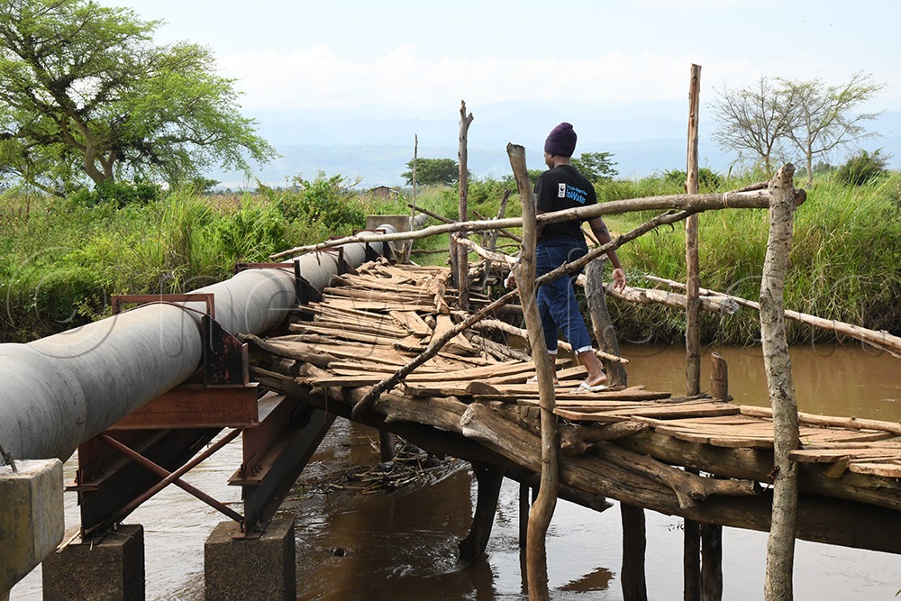 A young woman crosses River Sironko via a temporary bridge in Tajar village. (Photo by Mpalanyi Ssentongo)