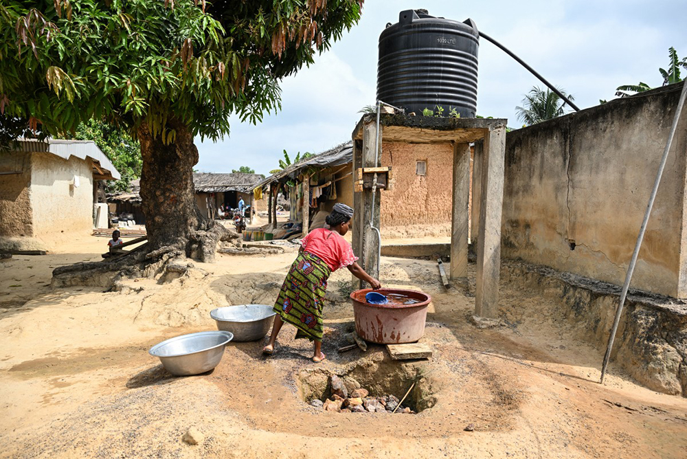 A woman draws water from a borehole in Betykro, a camp of cocoa producers living in precarious conditions 20 km from Guiglo, on January 16, 2026. (AFP)