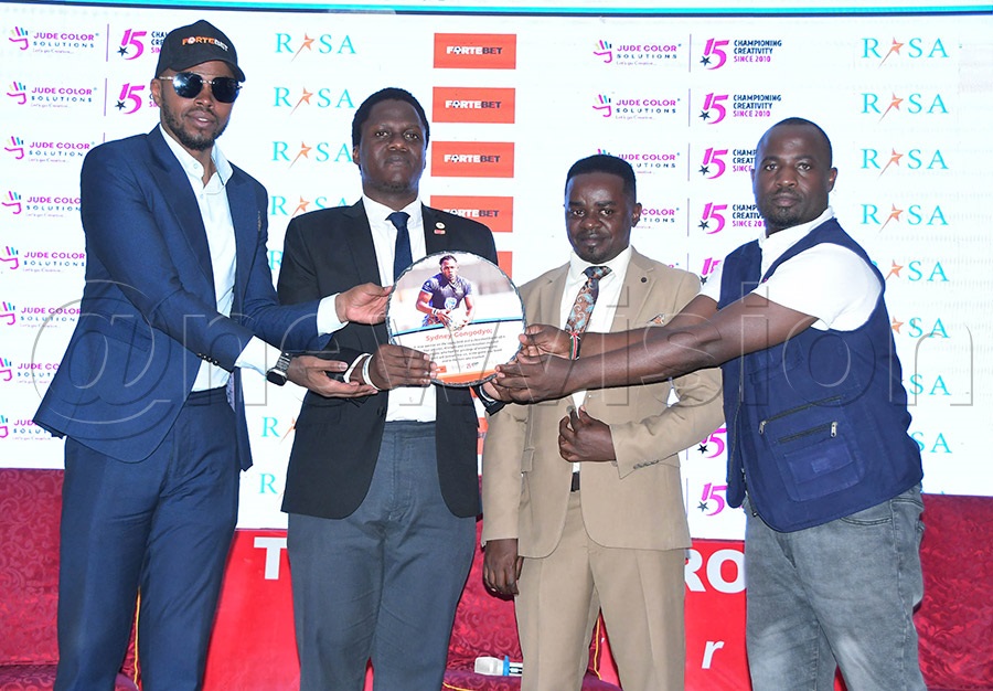 Stanbic Pirates Rugby Club manager Isaac Kimeze (second left) receives the Sydney Gongodyo commemorative plaque from Fortebet Real Stars officials. Photo: Silvano Kibuuka