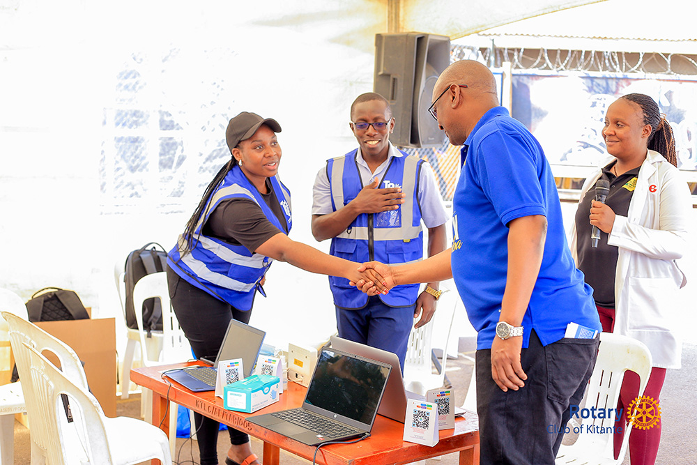Chief Guest DG Geoffrey Martin Kitakule shakes hands with one of the doctors deployed for patient diagnosis, as Dr Stella Namugerwa stands nearby holding a microphone during a tour of the ongoing activities at Kamyokya Treasure Life Center (TLC) in the Kamyokya community. (Courtesy photo)