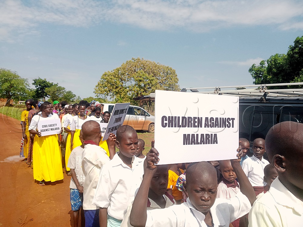 Children and other community members carrying placards during the regional Malaria Walk in Pader district. (Credit: Claude Omona)