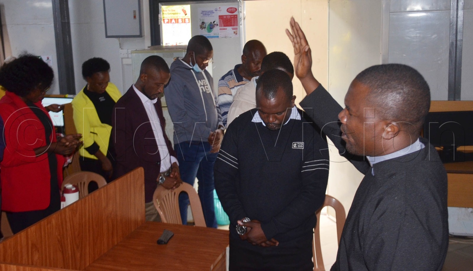 Rev. Dickson Nuwamanya (right), the chaplain of Bishop Stuart Teachers College, Kibingo and Nyamitanga institutions, praying for Vision Group staff. (Credit: Abdulkarim Ssengendo)